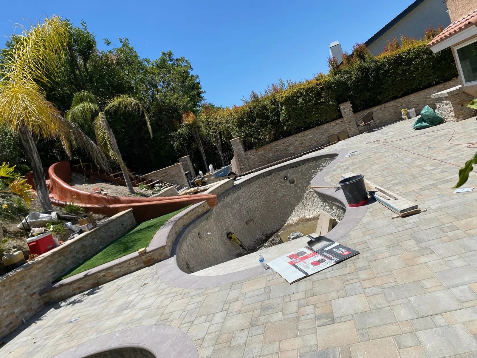 Paver pool patio with stacked-stone planter walls during a backyard renovation