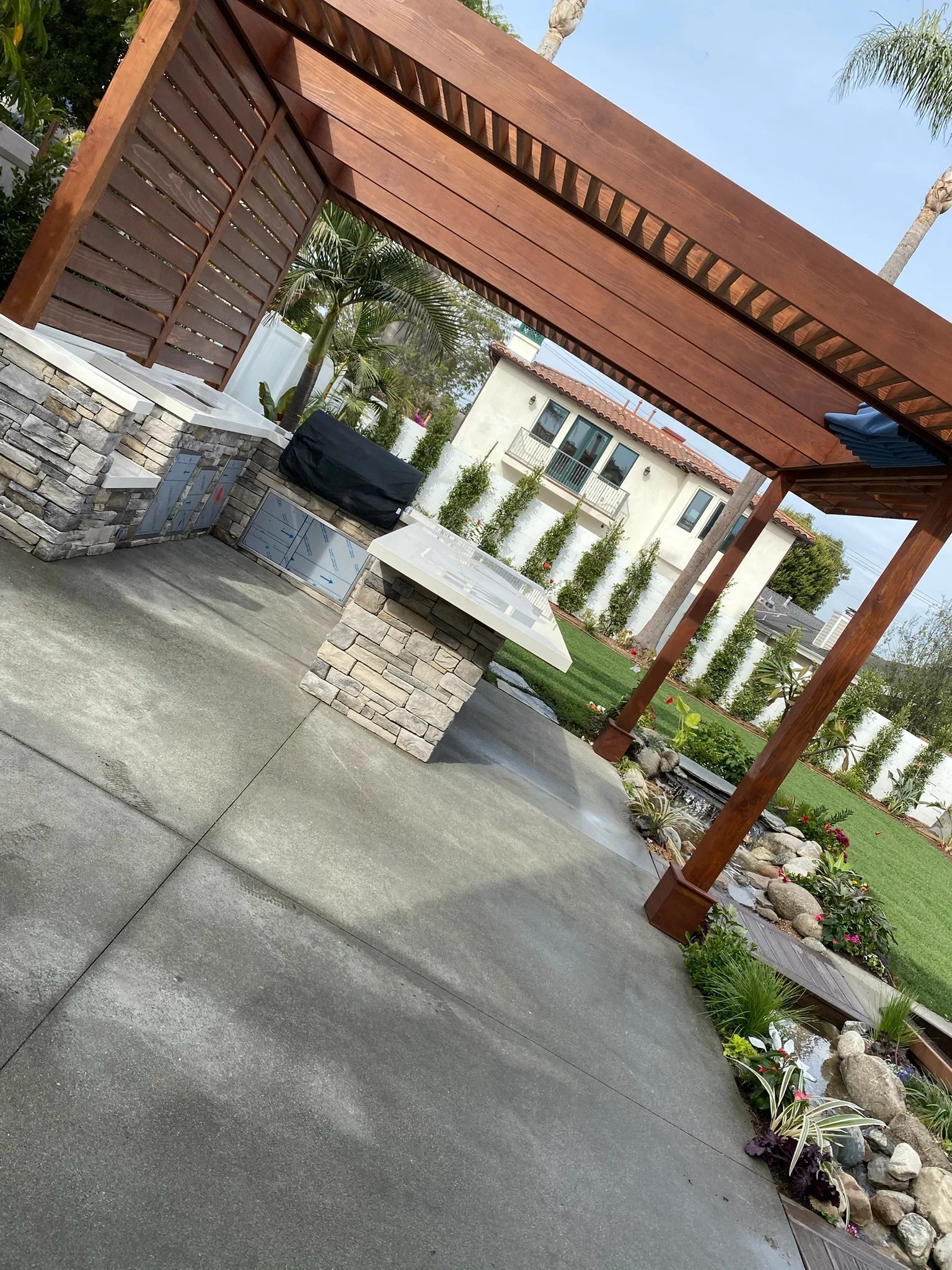 Outdoor kitchen with stone veneer island under a wood pergola