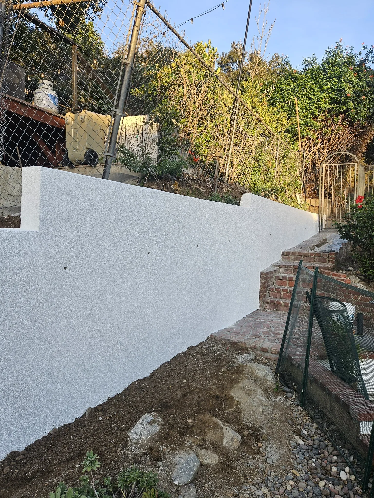Finished white stucco retaining wall along a property line