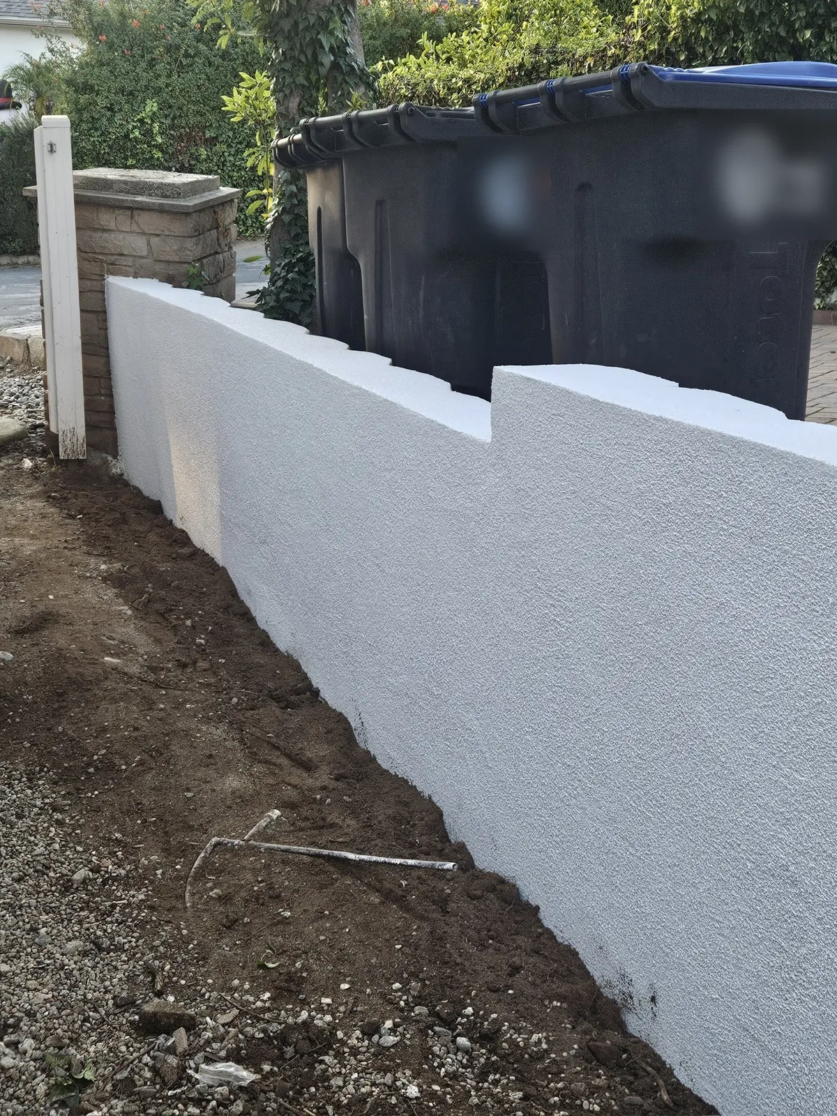 Low stucco-finished garden wall ending at a brick pilaster at a Glendale home