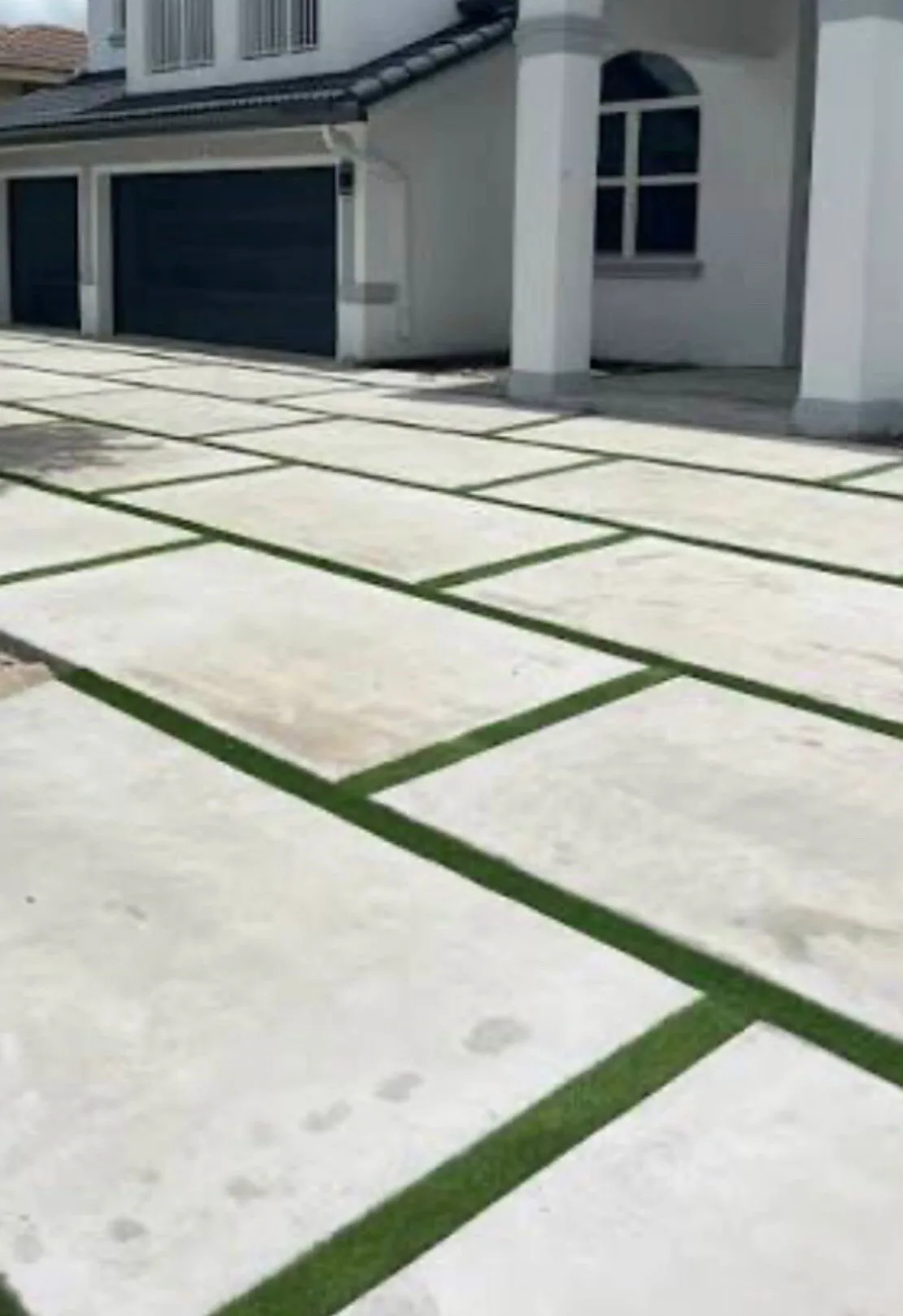 Finished concrete pad driveway with turf strips at a three-car garage in Los Angeles